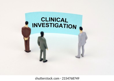 Medical Concept. Miniature Figures Of People Stand In Front Of A Blue Sign With The Inscription - Clinical Investigation