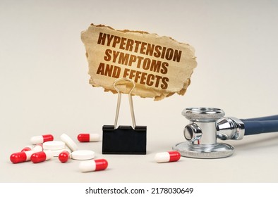 Medical concept. Near the stethoscope are pills and a clip with a cardboard sign - Hypertension Symptoms and Effects
