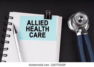 Medical concept. On a black surface, a stethoscope, a notebook, a pen and a blue sticker with the inscription - Allied Health Care - Shutterstock ID 2247752439