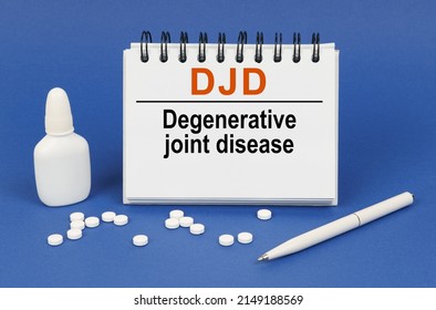 Medical Concept. On A Blue Background, A Pen, Tablets And A Notepad With The Inscription - DJD Degenerative Joint Disease