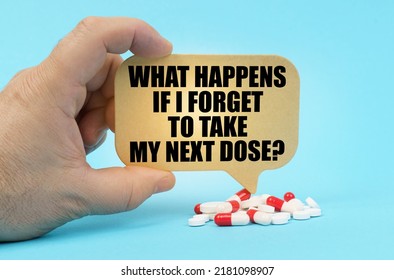 Medical Concept. On A Blue Surface Are Pills In A Persons Hand, A Sign With The Inscription - What Happens If I Forget To Take My Next Dose