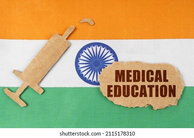 Medical Concept. On The Flag Of India, A Cardboard Figure Of A Syringe And A Torn Cardboard With The Inscription - MEDICAL EDUCATION