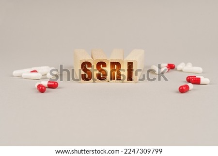 Medical concept. On a gray surface are pills and a red wooden block with the inscription - SSRI