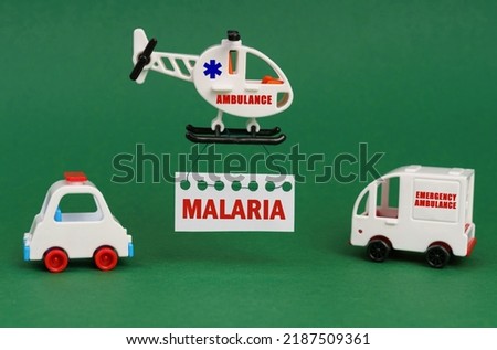 Medical concept. On a green surface, cars and an ambulance helicopter with a sign - malaria