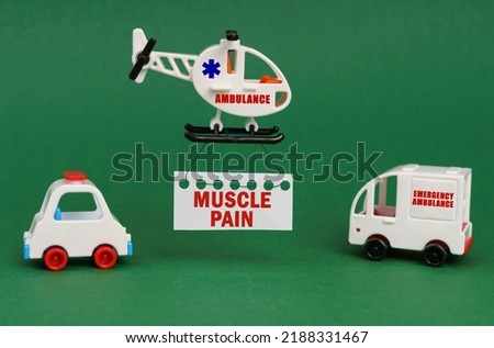 Medical concept. On a green surface, cars and an ambulance helicopter with a sign - Muscle pain
