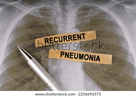 Medical concept. On a human chest x-ray, a pen and strips of paper labeled - recurrent pneumonia
