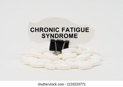 Medical concept. On a white surface are pills and torn paper with the inscription - Chronic fatigue syndrome