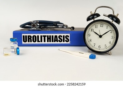 Medical concept. On a white surface, a thermometer, ampoules, a stethoscope, an alarm clock and a folder with the inscription - Urolithiasis - Shutterstock ID 2258242159