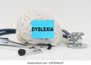 Medical concept. On a white surface next to the stethoscope lies a brain on which a sticker with the inscription - Dyslexia - Shutterstock ID 2395046167