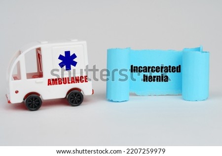 Medical concept. On a white surface, an ambulance and a blue paper sign with the inscription - Incarcerated hernia