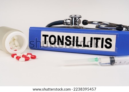 Medical concept. On a white surface there are pills, a syringe, a stethoscope and a folder with the inscription - Tonsillitis