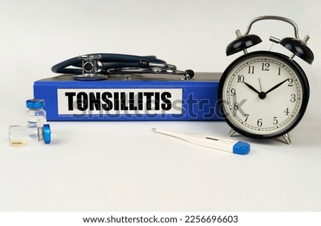 Medical concept. On a white surface, a thermometer, ampoules, a stethoscope, an alarm clock and a folder with the inscription - Tonsillitis