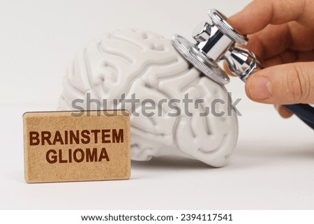 Medical concept. On a white surface, the brain is diagnosed using a stethoscope, next to it is a sign with the inscription - Brainstem glioma