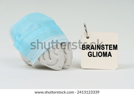 Medical concept. On a white surface next to the brain there is a notepad with the inscription - Brainstem glioma