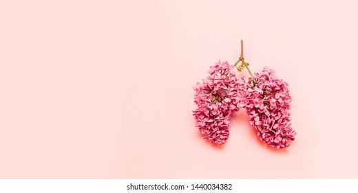 Medical concept of pink lilac flowers shaped in human lungs on pink background. Inflammation of the lungs concept, viral epidemic. Flat lay, top view. Harm of smoking