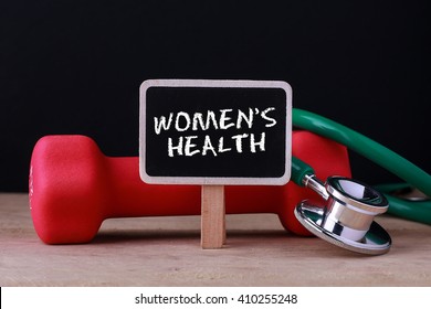 Medical concept - Stethoscope and dumbbell on wood with WOMEN'S HEALTH word