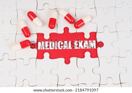 Medical concept. There are pills on the white puzzles, in the middle there is a red surface with the inscription - MEDICAL EXAM