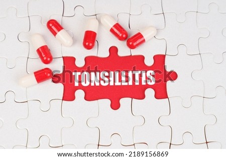 Medical concept. There are pills on the white puzzles, in the middle there is a red surface with the inscription - Tonsillitis