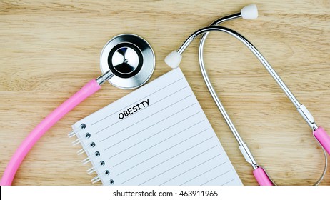 Medical Concept. Top View Of Pink Stethoscope And Notebook On The Wooden Table With Text.