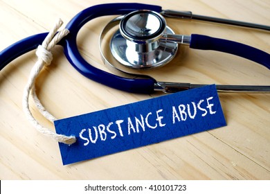 Medical conceptual image with SUBSTANCE ABUSE word written on label tag and stethoscope on wooden background.