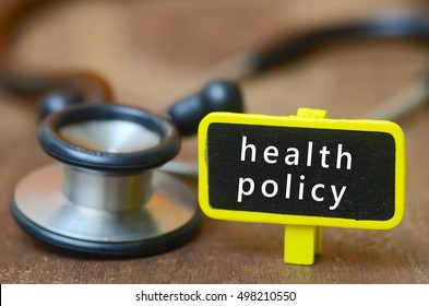 Medical Concept.Word HEALTH POLICY And Signage With Stethoscope On Wooden Table.