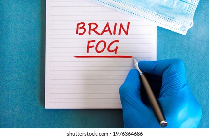 Medical, COVID-19 Pandemic Coronavirus Brain Fog Symbol. Doctor Hand. White Note With Words 'brain Fog'. Metallic Pen. Beautiful White Background. Copy Space. Medical And Covid-19 Brain Fog Concept.