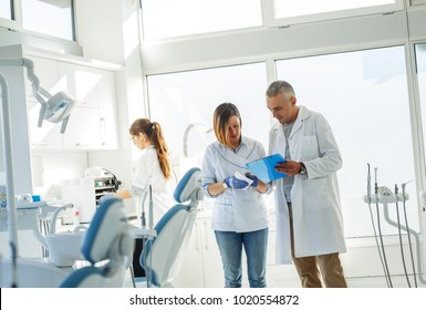 Medical dentist team in dental office   examining list of patients.
