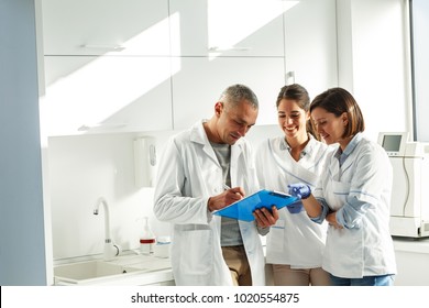 Medical Dentist Team In Dental Office   Examining List Of Patients.