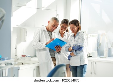 Medical Dentist Team In Dental Office   Examining List Of Patients.