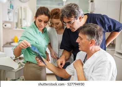 Medical dentist team in dental office discuss and examining x-ray image.