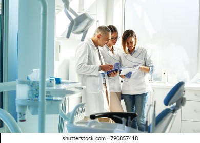 Medical dentist team in dental office discuss about practice and examining list of patients.