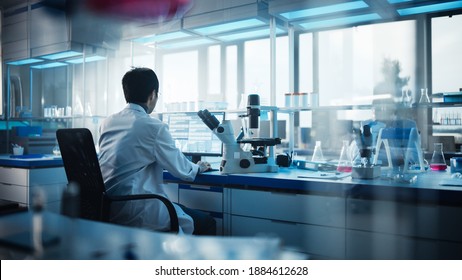 Medical Development Laboratory: Back View of Japanese Male Scientist Using Touch Screen Digital Tablet Computer, Doing Data Analysis Research. Biotechnology Specialists in Advanced Scientific Lab - Powered by Shutterstock