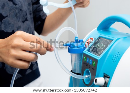 Medical Device Individual Blue White portable oxygen cylinder to put gas for patients with respiratory disorders, woman hand try to plug in the rubber tube to tank