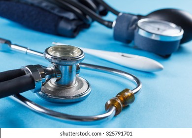 Medical devices stethoscope, tonometer, and thermometer on blue background