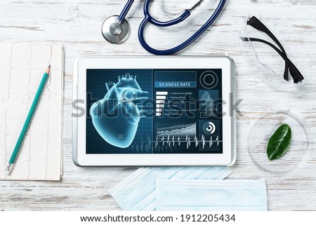 Medical diagnostics in hospital. Tablet computer with medical app interface on screen. Doctor workplace with stethoscope and cardiogram on wooden desk. Digital technology in cardiology clinic.