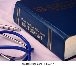 Medical Dictionary Laid On A Doctors Desk, Also Showing Doctors Blue Stethoscope And Pen