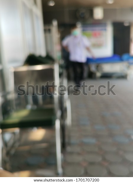 Medical disability mobility care service concept\
with blur wheelchairs and stretchers background in front of blurry\
hospital center at drop-off car parking area at building entrance\
hall