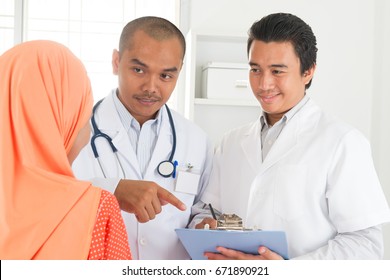 Medical Doctor Explaining Health Result To Patient. Southeast Asian Muslim People.