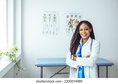 Medical Doctor Indoors Portraits. Portrait Of A Confident Doctor Working At A Hospital. Waist Up Portrait Of Beautiful African-American Nurse Posing Confidently While Standing With Arms Crossed