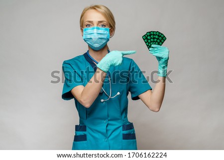 medical doctor nurse woman wearing protective mask and rubber or latex gloves - holding blisters of pills