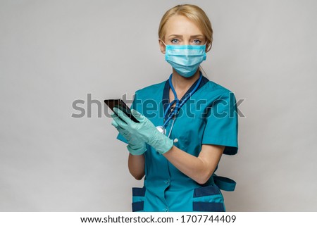 medical doctor nurse woman wearing protective mask and latex gloves - using mobile phone