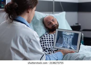 Medical doctor presenting options to patient for treating throat affliction while looking at mri scan on digital tablet. Middle aged man with cervical issues having low oxygen saturation. - Shutterstock ID 2138273755