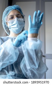 A medical doctor putting on protective blue gloves