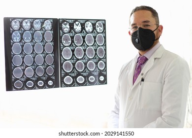 Medical Doctor Specialized In Neurology With A Mask And A Gown Uniform Reviews X-rays Of The Brain Or CT Scans As His Professional Work
