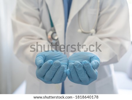 Medical doctor or surgeon with empty hands in hygience lab gloves offering or holding copy space for health care practice, nursing, organ donation, hospital csr, or clinical charity concept 