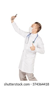 Medical Doctor In White Coat With Stethoscope And Mask Taking A Selfie With Front Camera Smiling.Isolated Over White Background.