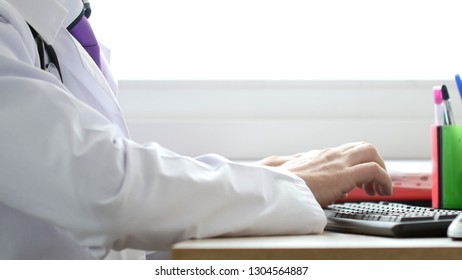 Medical Doctor Working On Laptop In His Cabinet And Clicking Computer Mouse.