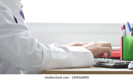 Medical Doctor Working On Laptop In His Cabinet And Clicking Computer Mouse.