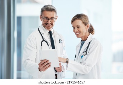 Medical, Doctors And Healthcare Professionals Working Together On A Digital Tablet In A Hospital. Portrait Of A Mature Female And Male Doctor Smiling And Discussing Diagnosis In A Clinic.