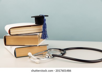 Medical education concept. Stethoscope and graduation cap on stack of books on blue background
